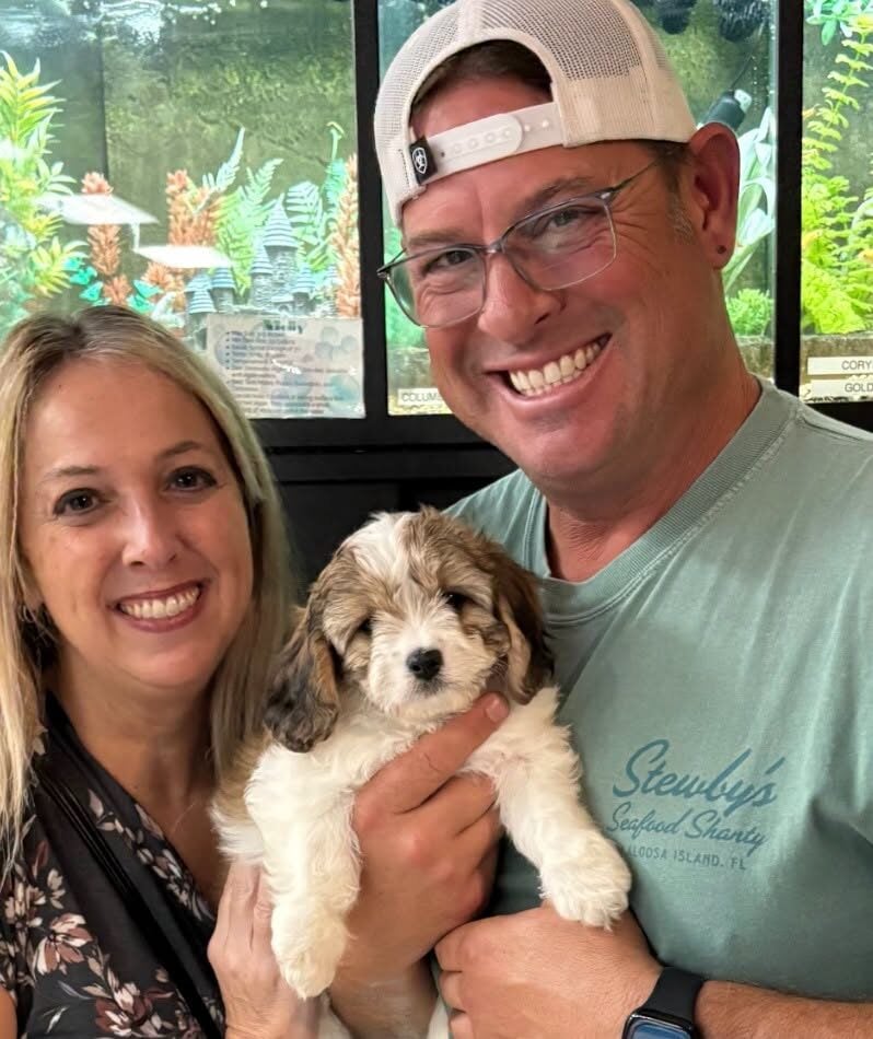 A smiling couple holding their new puppy at Petland Terre Haute